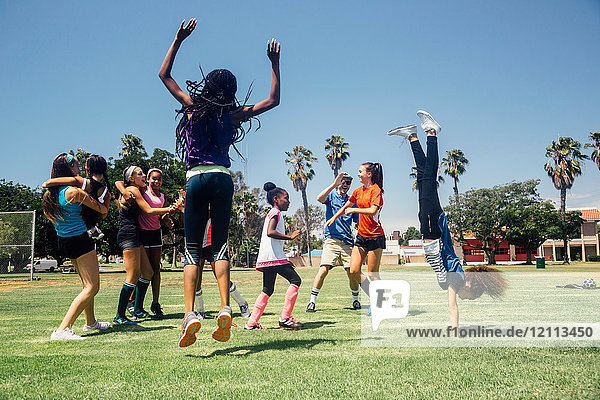 Schulmädchen-Fussballmannschaft springt vor Freude auf dem Schulsportplatz
