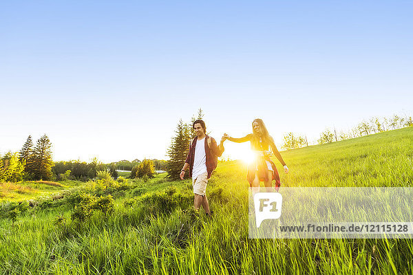 Junges Paar  das zusammen in einem Stadtpark bei Sonnenuntergang spazieren geht; Edmonton  Alberta  Kanada