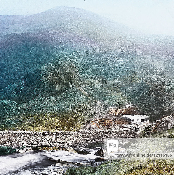 Magic Lantern slide circa 1900 hand coloured. created in 1887. A tour of North Wales. 31.View at Nant Mill—To get this view we can either descend Snowdon on the Llanberis side  and then take train  vid Carnarvon  for Bettws Garmon  or we can find our way over the mountain to Snowdon Hanger  and so along the valley. If we choose the former we have a pleasant ride along the peculiar little narrow-gauge railway  with its fine views  and the picture before us may be seen from the carriage windows as we pass along. This is a charming spot  and has long been a favourite haunt of the artist. Although the old Mill is gone  there remains still such a picture of exquisite beauty  that one cannot help a feeling of intense pleasure at the sight.
