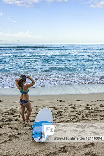 Junge Surferin bereitet sich am Strand darauf vor  ins Wasser zu gehen; Honolulu  Oahu  Hawaii  Vereinigte Staaten von Amerika