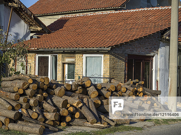 Ein Haus mit einem großen Stapel gefällter Baumstämme im Vorgarten und schweren Geräten auf dem Dach; Kladovo  Bezirk Bor  Serbien