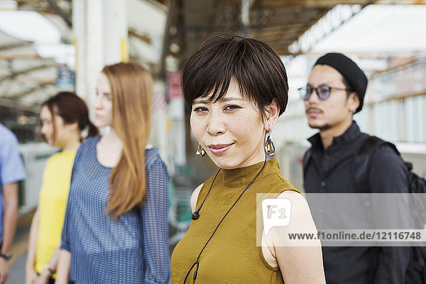 Small group of people standing on the platform of a subway station Tokyo commuters.