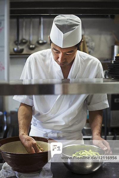 Chefkoch  der in der Küche eines japanischen Sushi-Restaurants arbeitet und eine Schüssel Edamer-Bohnen zubereitet.