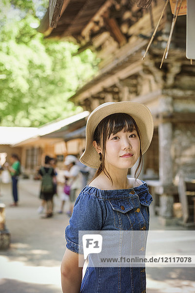 Junge Frau in blauem Kleid und Hut im Shinto Sakurai-Schrein  Fukuoka  Japan.