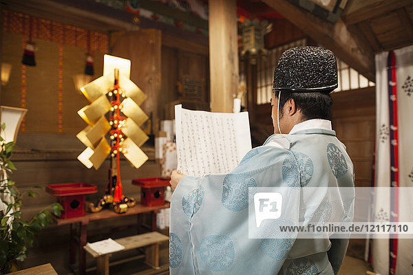 Rückansicht eines Priesters mit einer Schriftrolle im Shinto-Sakurai-Schrein  Fukuoka  Japan.