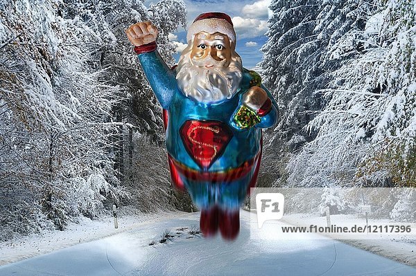 Weihnachtsmann als Superman  Weihnachtsbaumfigur in einem verschneiten Wald
