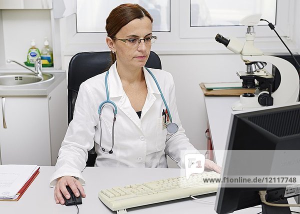 Ärztin bei der Arbeit an einem Computer am Schreibtisch