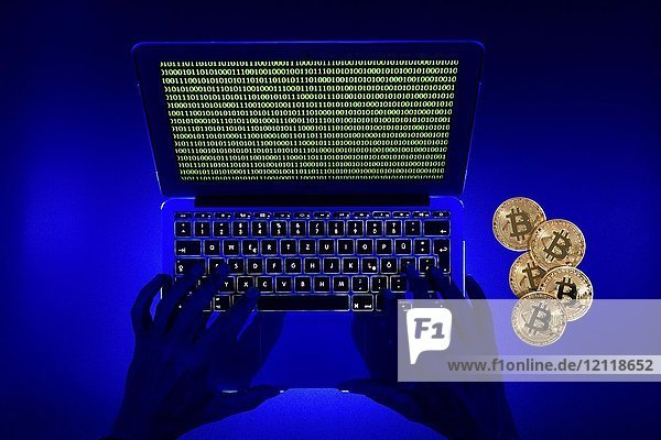 Symbolbild digitale Währung  goldene physische Münze bitcoin Laptop mit digitalen binären Händen
