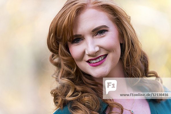 Portrait of a smiling 27 year old redhead woman outdoors.
