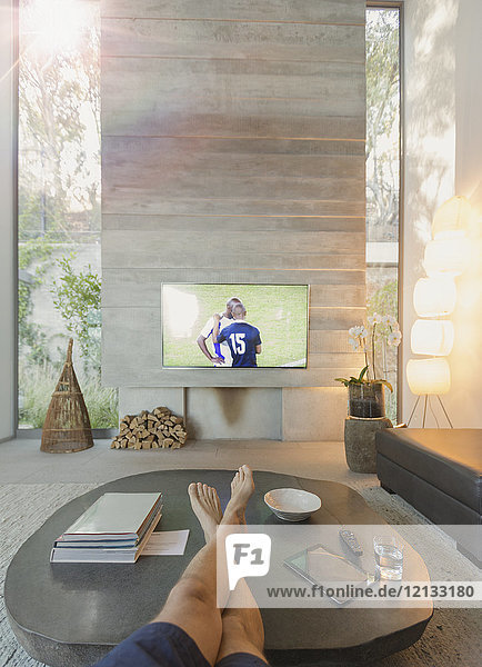 Persönliche Perspektive Mann schaut Fußball im Fernsehen im Wohnzimmer