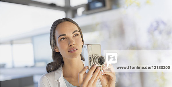 Serious brunette woman using digital camera