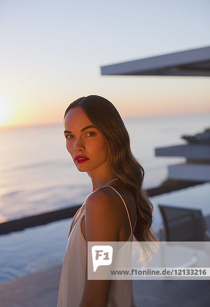 Porträt ernst  schöne Frau auf Sonnenuntergang Terrasse mit Meerblick