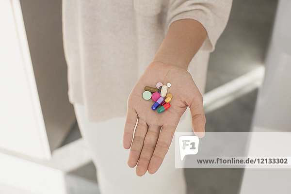 Frau hält  zeigt mehrfarbige Pillen