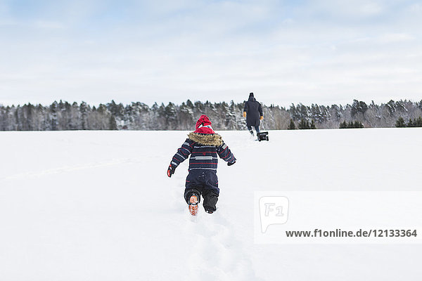 Rückansicht des im Schnee spielenden Kindes