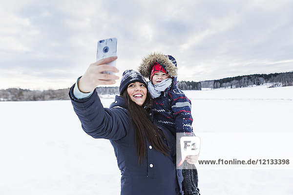 Mother taking selfie with son in snow