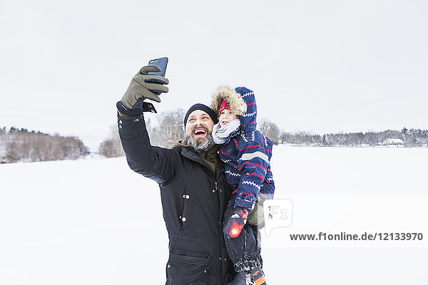 Vater nimmt Selfie mit Sohn im Schnee mit.