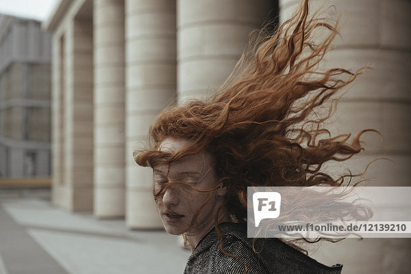 Wind weht Haare der kaukasischen Frau in der Nähe von Säulen