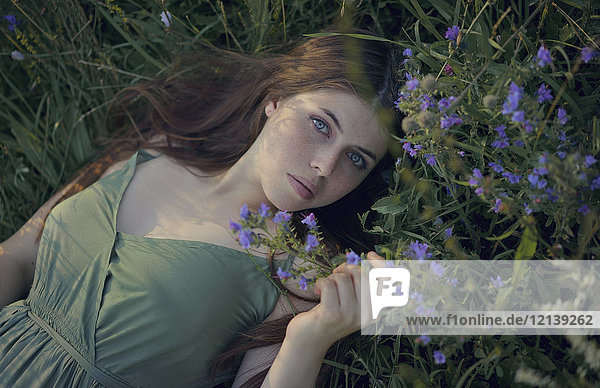 Caucasian woman laying in grass with wildflowers
