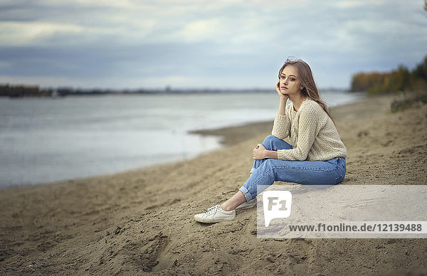 Nachdenkliche Frau am Strand sitzend