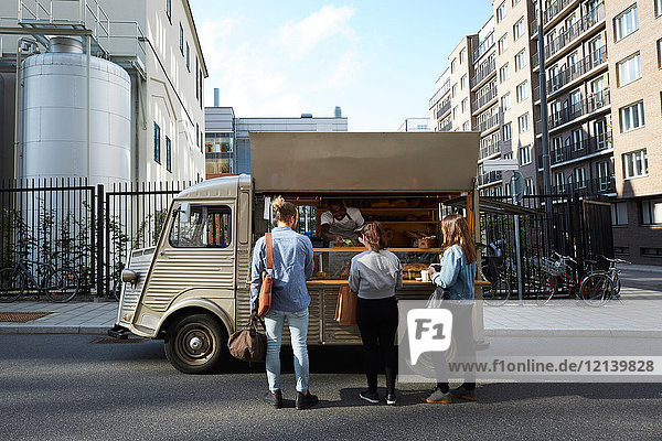 Kunden kaufen Brot vom Verkäufer am Lebensmittelwagen der in der Stadt geparkt ist.