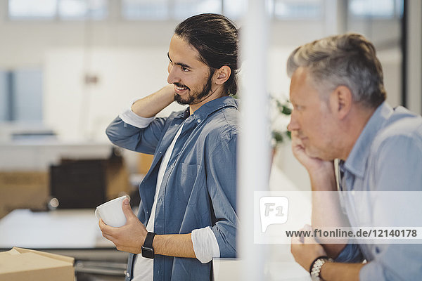 Smiling young businessman holding coffee cup in new office