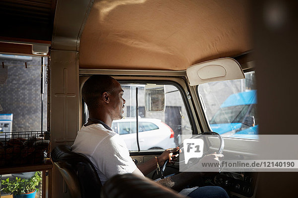 Side view of mid adult man driving food truck in city