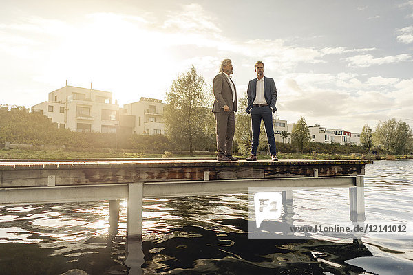 Zwei Geschäftsleute stehen auf einem Steg am See