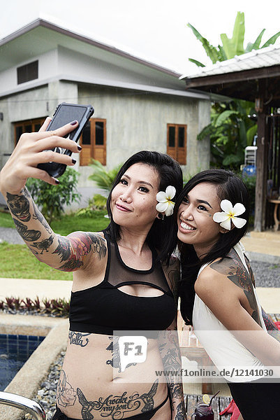 Two happy women taking a selfies at swimming pool