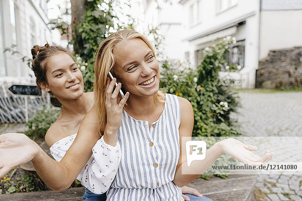 Zwei glückliche junge Frauen mit Handy in der Stadt