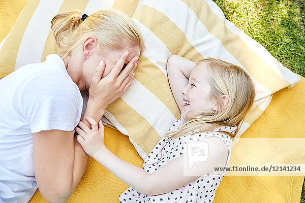 Happy girl with mother lying on a blanket