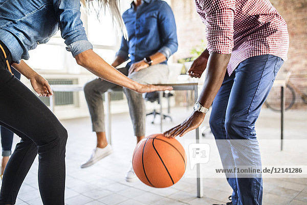 Colleagues playing basketball in office