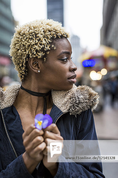 Porträt einer Frau mit gefärbtem Haar  die eine Blume hält.
