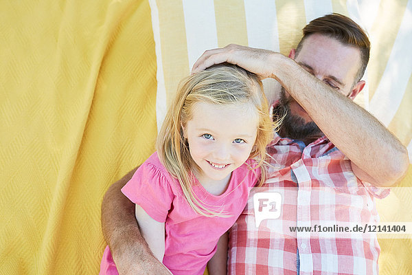 Glückliches Mädchen mit Vater auf einer Decke liegend