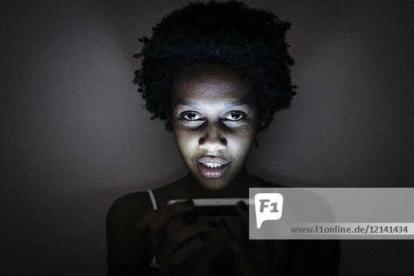 Porträt einer jungen Frau mit Handy im Dunkeln