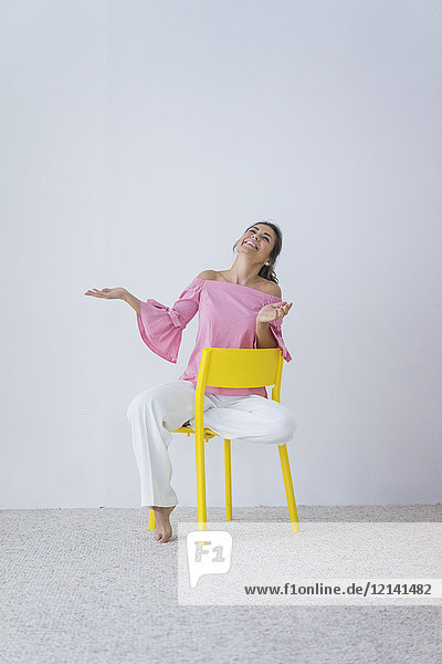 Portrait of laughing woman sitting on yellow chair