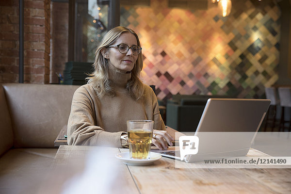 Portrait einer Geschäftsfrau bei der Arbeit am Laptop in einem Restaurant