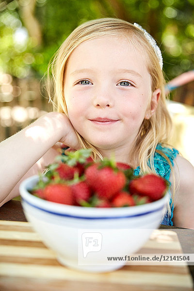 Porträt eines lächelnden Mädchens mit Schale mit Erdbeeren