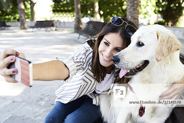 Fröhliche junge Frau nimmt Selfie mit ihrem Hund mit