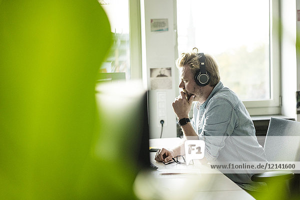 Businessman wearing headphones at desk in office