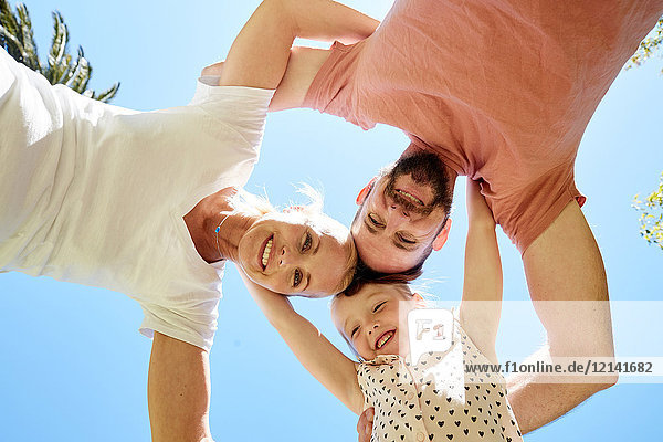 Portrait of happy family huddling under blue sky