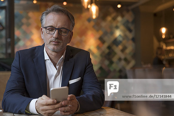 Portrait eines Geschäftsmannes mit Smartphone in einem Restaurant