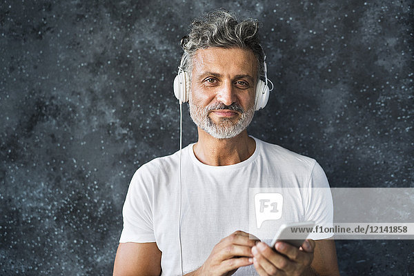 Portrait of a mature man using smartphone  wearing headphones