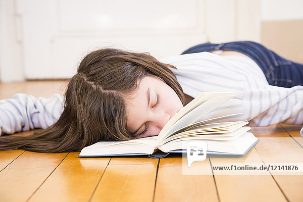 Mädchen mit Buch auf dem Boden liegend schlafend