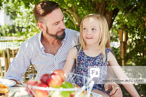 Girl with father sitting at garden table