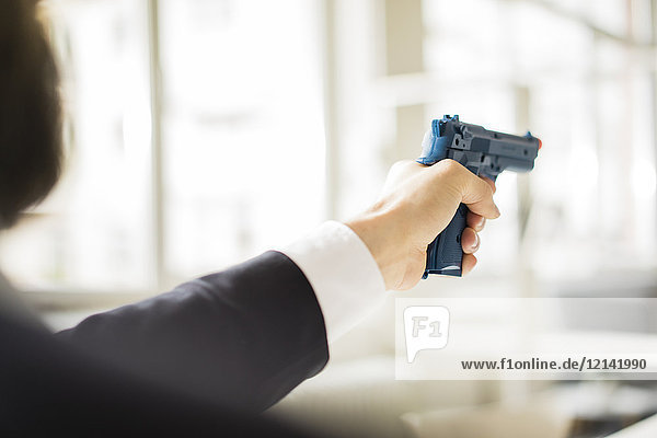 Businessman aiming with gun in office