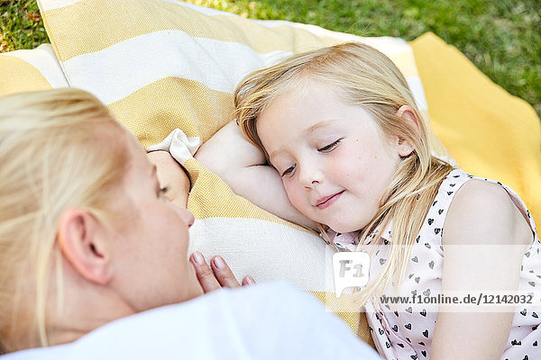 Lächelndes Mädchen und Mutter auf einer Decke liegend