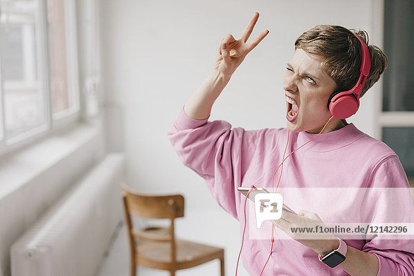 Woman with cell phone and headphones posing while listening to music