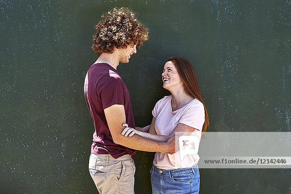 Lächelndes junges Paar vor einer grünen Wand