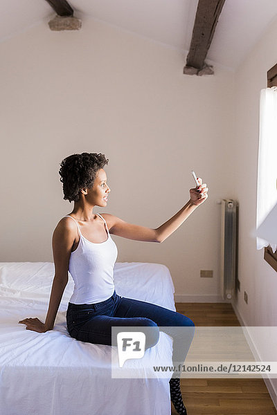 Junge Frau  die einen Selfie im Schlafzimmer nimmt.