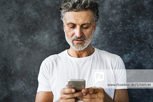 Reifer Mann mit Smartphone  der Textnachrichten sendet